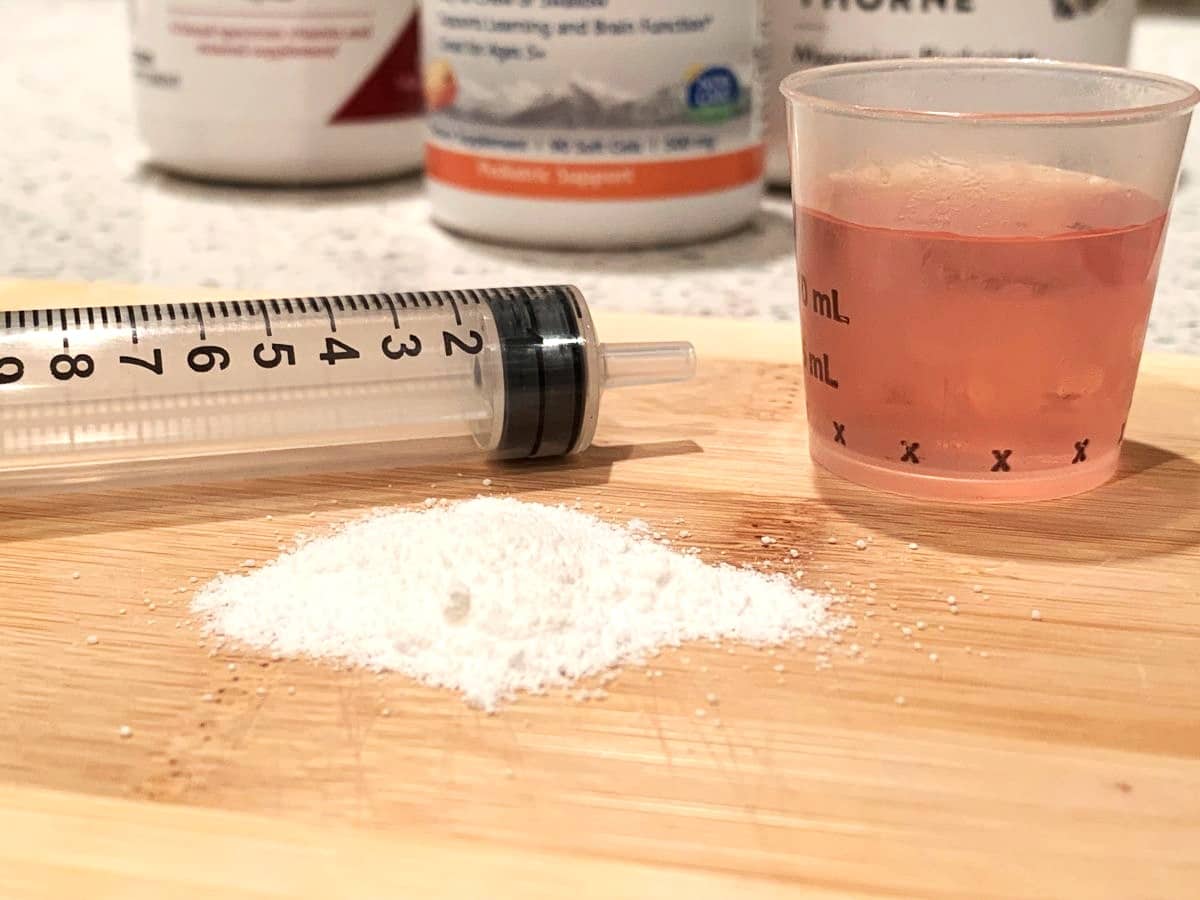 image of multivitamin powder, juice and medicine syringe to show one way of administering vitamins to picky eaters