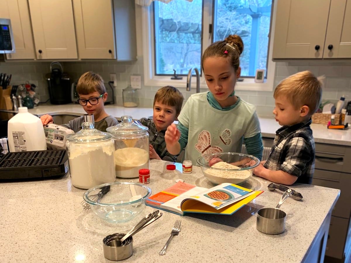 4 children in the kitchen, measuring ingredients to make waffles